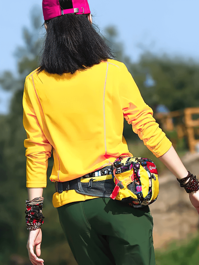 Woman in a yellow quick-drying stand-up collar top, wearing a colorful belt bag and green pants, perfect for active lifestyles.